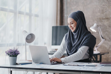 happy muslim business women in hijab at work smiling arab woman taking notes and work on laptop