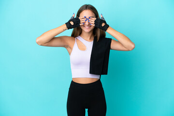 Young sport woman isolated on blue background covering eyes by hands