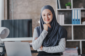 happy muslim business women in hijab at work smiling arab woman taking notes and work on laptop