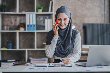 happy muslim business women in hijab at work Smiling Arab woman talking on smartphone, taking notes...