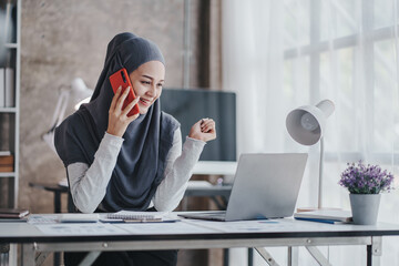 happy muslim business women in hijab at work Smiling Arab woman talking on smartphone, taking notes...