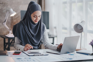 happy muslim business women in hijab at work smiling arab woman taking notes and work on laptop