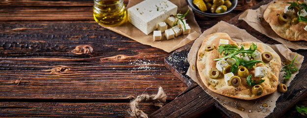 Delicious homemade flatbread with cheese olives and herbs on table - obrazy, fototapety, plakaty