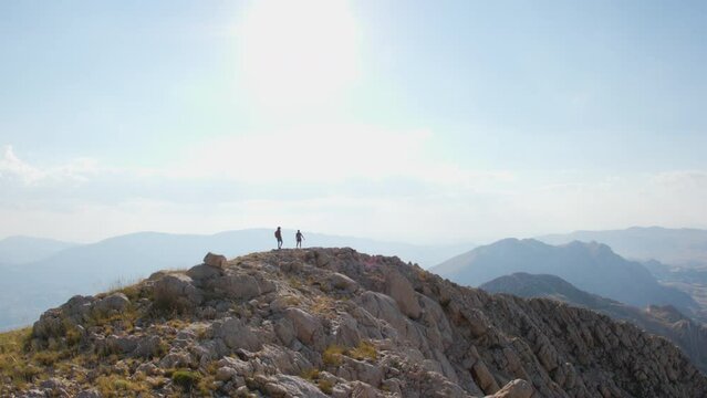two girls with backpacks walk along a mountain path. trekking and vacation adventure. climbing and freedom.
