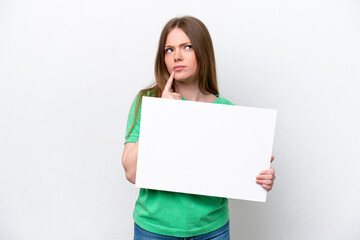 Young caucasian woman isolated on white background holding an empty placard and thinking