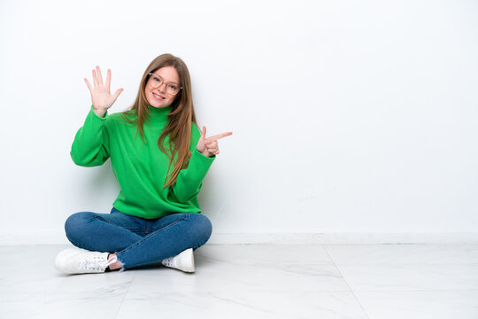 Young caucasian woman sitting on the floor isolated on white background counting seven with fingers