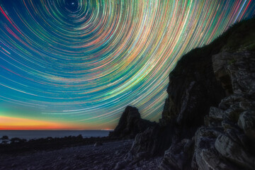 Star trails over rocky coast in Devon, UK.