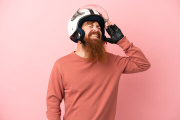 Young reddish caucasian man with a motorcycle helmet isolated on pink background smiling a lot