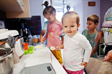 Mother with kids cooking at kitchen, happy children's moments.