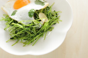 Chinese food, Pea sprouts stir fried vegetable with sunny side up fried egg on top