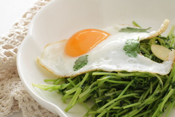 Chinese food, Pea sprouts stir fried vegetable with sunny side up fried egg on top