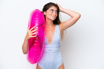 Young woman in swimsuit holding an air mattress donut isolated on white background having doubts and with confuse face expression