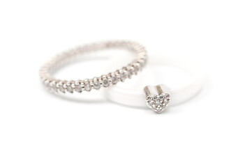 A white ceramic ring with a metal heart decorated with rhinestones and a silver ring with decorative stones.