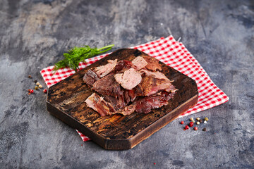 Pieces of baked meat on cutting board on gray background