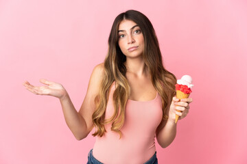 Young caucasian woman with a cornet ice cream isolated on pink background having doubts while raising hands