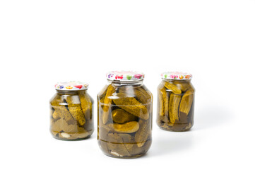 Fresh canned cucumbers in three jars, hermetically sealed with metal lids.