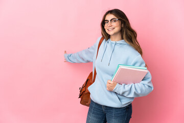 Fototapeta premium Young student woman isolated on pink background extending hands to the side for inviting to come