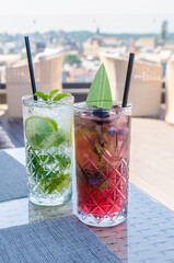 Refreshing drinks mojito cocktails with berries lime crushed ice on a blurred background.