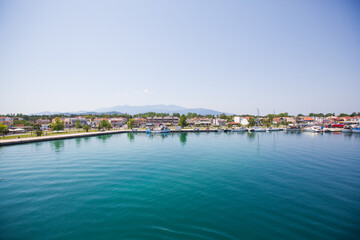 Naklejka na ściany i meble Panoramic view of Keramoti, small town, and port in Greece. Seascape. Beautiful blue water and sky. Summer day. Travel holiday vacation. 