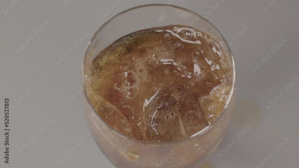 Poster high angle view of ice cube falling into glass of cola with the liquid splashing in slow motion