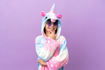 Obraz na płótnie Canvas Little kid wearing a unicorn pajama isolated on purple background with glasses and smiling