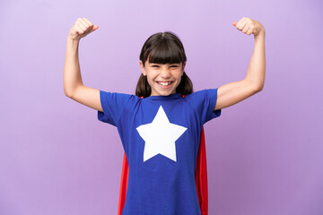 Little kid isolated on purple background in superhero costume and doing strong gesture