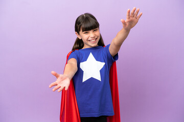 Little kid isolated on purple background in superhero costume and doing coming gesture