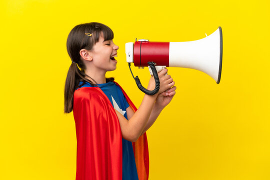 Little super hero kid isolated on purple background shouting through a megaphone