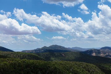 Beautiful view of a valley with hills and mountains under the sky with puffy clouds