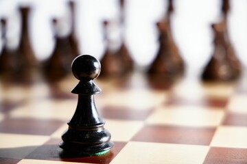 Black chess pawn on a wooden board - intimidation, strategy concept