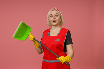 cleaning lady in an apron and gloves with a dustpan in her hands on a colored background