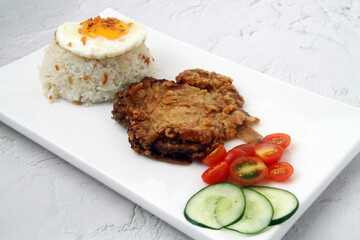 Freshly cooked Filipino food called Pork Chop Silog or pork chop, egg and fried rice
