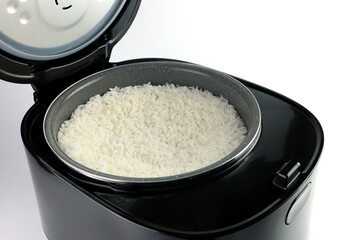Thai jasmine rice is cooked in a modern design digital black rice cooker for breakfast and is put on the white table with in the white modern kitchen