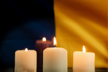 A group of burning candles against the background of the national flag of Ukraine