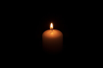 Burning wax candle on a black background