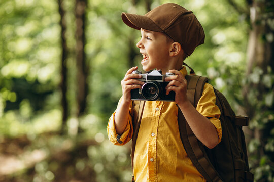 Little boyscout making photos on camera at the forest