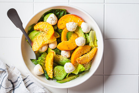 Summer peach salad with avocado, cucumber and mozzarella. Healthy recipe, vegetarian food concept.