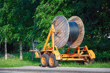 Wooden reel with fiber optic cable mounted on trailer for easy transportation. Laying optical fiber...