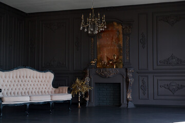 Fototapeta premium Black room interior with a vintage sofa, chandelier, mirror and fireplace