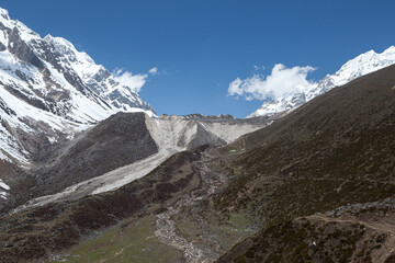 View of the trail between high mountain snow-capped peaks in the Himalayas in the Manaslu region