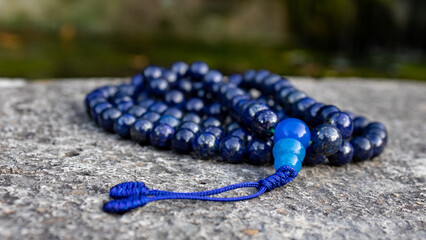 Blue buddhist mala prayer beads (lapislazuli) on stone, close up. Mindfulness and japa meditation...