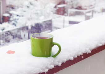 Obraz na płótnie Canvas Ceramic mug with hot tea on the snowy balcony, 