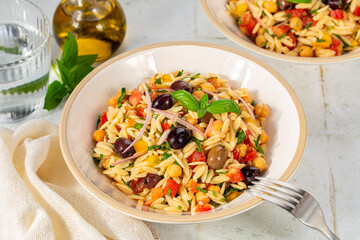 Orzo pasta salad with vegetables. Olive taggiasche, tomato, bell pepper, chickpeas, red onion,...