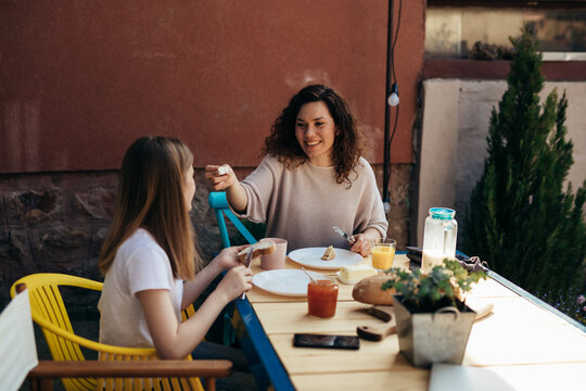mother and daughter having breakfast together in backyard at home