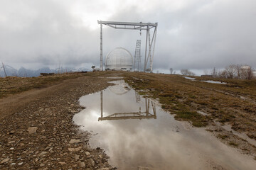 Astrophysical observatory in the Arkhyz mountains with reflection in a puddle