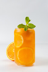 cold orange cocktail with ice decorated with mint leaf