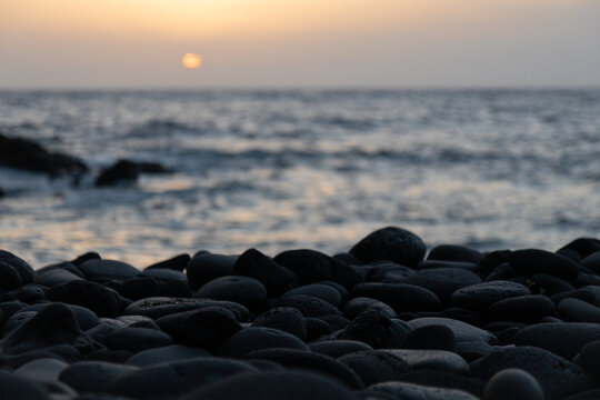 Sunset in Tenerife. Black volcanic pebbles and Atlantic Ocean.