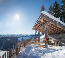 viewpoint at Hartkaiser mountain with wooden shelter and picket fence, sunny winter landscape tirol