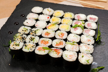 a set of maki rolls with different fillings on a black stone plate