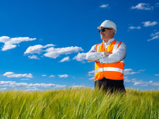 Confident man engineer. Engineer in white helmet on field. Employee engineering bureau against...
